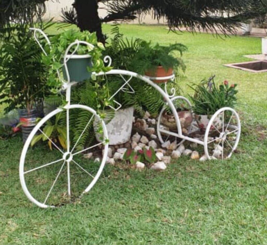 White wrought-iron bicycle plant stand holding potted plants on a lawn